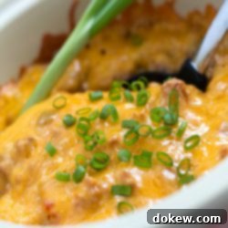 Sizzling Fiesta Bake 2 South of the Border Casserole in a white bowl with a serving spoon.