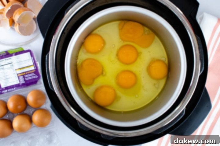 instant-pot-no-peel-egg-salad-ip-1-min Image showing overhead view of cracked eggs in an inner pot inside Instant Pot with a carton of eggs to the side