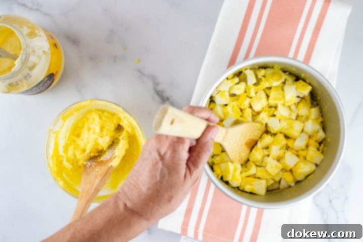 instant-pot-no-peel-egg-salad-ip-6-min Overhead view of hard boiled eggs being broken up with a wooden spatula with a separate bowl containing a mayonnaise and yolk mixture