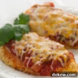 Vibrant Santa Fe Chicken 2 Two golden-brown, breaded chicken breasts generously topped with bright red salsa and a blanket of melted shredded Mexican cheese, served on a pristine white plate, ready to enjoy.