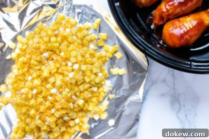 Foil Packet for Seasoned Potatoes A generous piece of aluminum foil holds a delicious mixture of diced potatoes, shredded cheddar cheese, and diced onions, perfectly prepped for a foil packet. Beside it, a slow cooker contains three chicken breasts simmering in rich barbecue sauce, all set for layering in this convenient Crockpot BBQ Chicken Dinner.