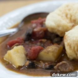 Slow-Cooked Beef Stew with Fluffy Dumplings 2 Close-up of a serving of homemade beef stew with tender beef chunks, vegetables, and two light, fluffy dumplings.