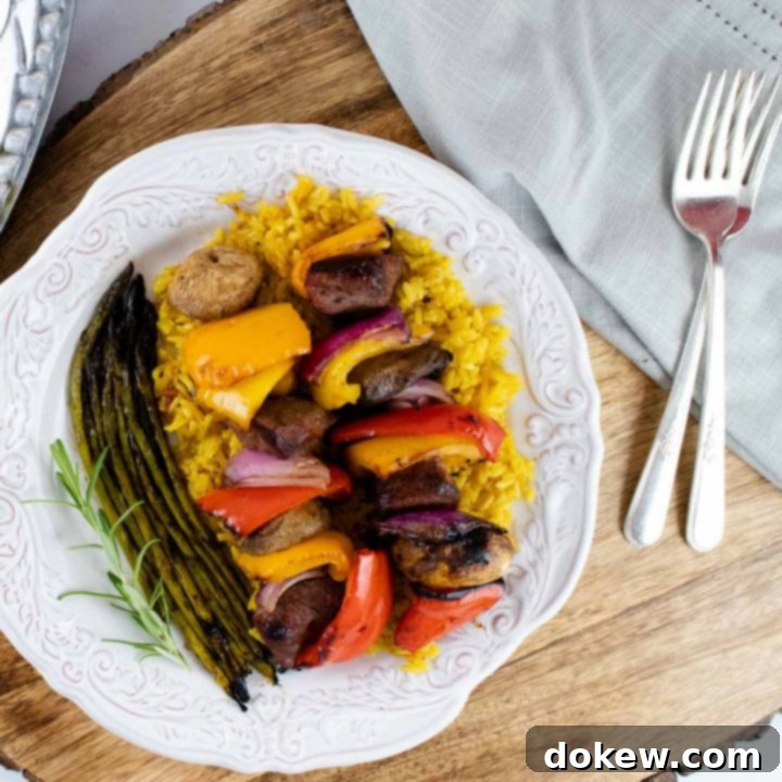 soy-garlic-beef-marinade-insta-min plate of cooked beef and vegetable kabobs over yellow rice served with grilled asparagus
