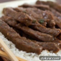 Sweet and Savory Mongolian Beef 2 Sliced steak with a sauce on a bed of rice with chopsticks in the foreground.