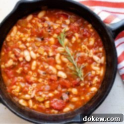 Hearty Italian Pasta and Beans 2 Cast iron skillet with Pasta e Fagioli, a soup made with pasta,tomatoes, chopped celery and onion, cannellini beans, and tomato sauce.