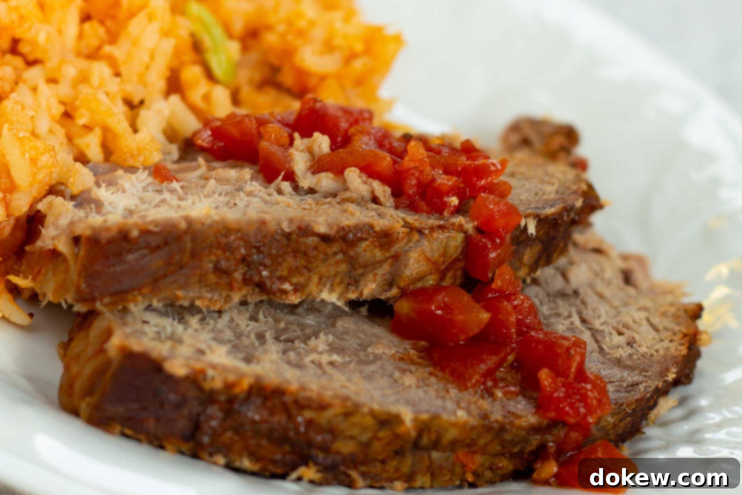 Ultimate Slow Cooker Mexican Pot Roast 4 Platter of perfectly sliced Mexican pot roast with a side of fluffy Mexican rice and a garnish of fresh herbs.