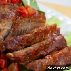 Ultimate Slow Cooker Mexican Pot Roast 5 Sliced pot roast with diced tomatoes on top and a red sauce.
