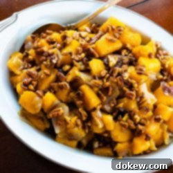 Harvest Gold Squash with Sweet Pecan Crunch 2 A beautifully presented bowl of golden roasted butternut squash mixed with onions and topped with glistening candied pecans, perfect for a holiday meal.