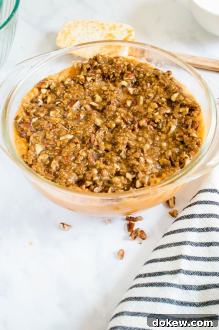 sweet-potato-casserole-ip-6-min Round glass baking dish filled with smooth sweet potato casserole and generously topped with streusel, ready for the oven