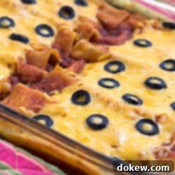 Hearty Beef Enchilada Bake 2 Glass casserole dish with enchiladas topped with melted cheese and sliced black olives.