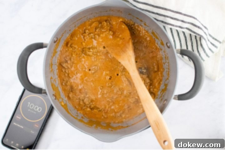 freezer-friendly-penne-pasta-bake-ip-4-min Overhead view of unbaked penne pasta bake topped with shredded cheese in a glass pan