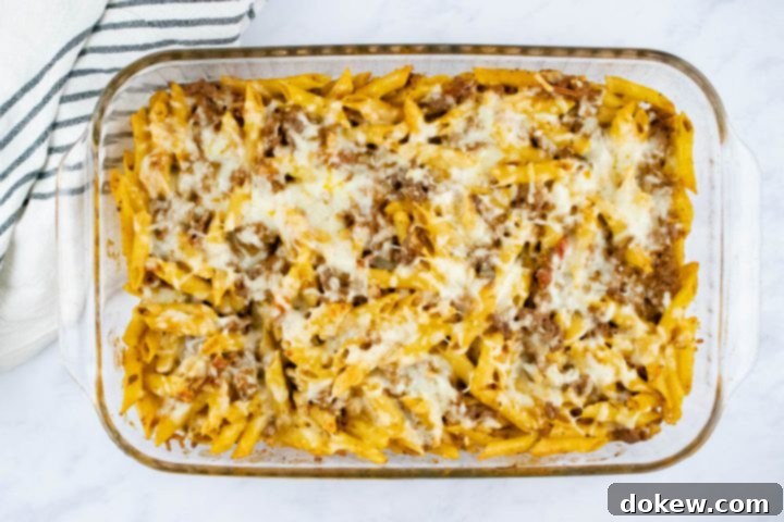 freezer-friendly-penne-pasta-bake-ip-7-min Overhead view of baked penne pasta bake topped with shredded cheese in a glass pan
