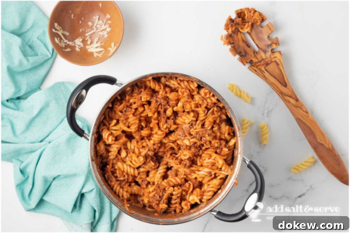 Creamy Cheesy Spirals 6 Large pot with spiral pasta with cheese and ground beef served in white bowls.