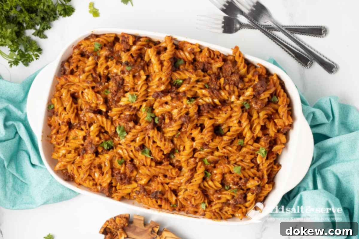 Creamy Cheesy Spirals 8 Spiral pasta bake in a white casserole dish garnished with fresh parsley.