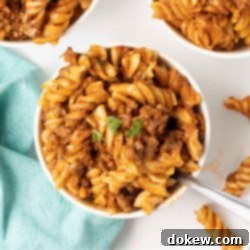 Creamy Cheesy Spirals 10 Spiral pasta bake with cheese and ground beef served in white bowls.