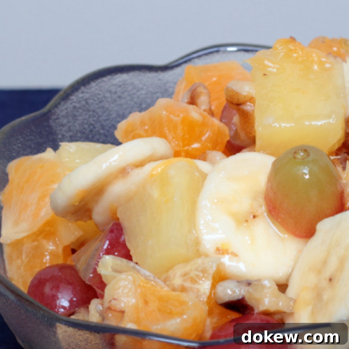 Paradise Fruit Medley 2 A vibrant bowl of tropical fruit salad featuring grapes, chopped oranges, pineapple chunks, sliced bananas, and crunchy walnuts.