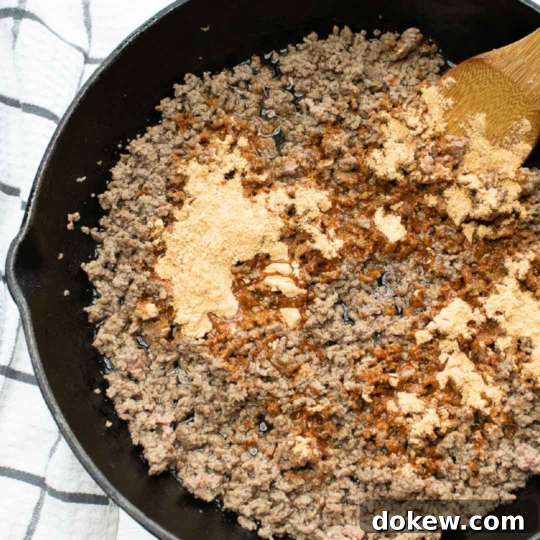 The Integrated Architecture 2 Overhead shot of ground beef in a cast iron skillet with taco seasoning on top