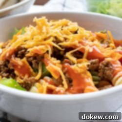 Taco Macaroni Salad 5 Bowl of seasoned ground beef, spiral pasta, lettuce, halved tomatoes, nacho cheese Doritos, and French salad dressing with shredded cheddar cheese on top