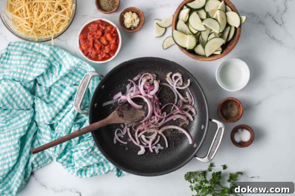 Fresh Zucchini Linguine 5 Sliced red onion sautéing in a skillet, surrounded by prepared ingredients for zucchini linguine.