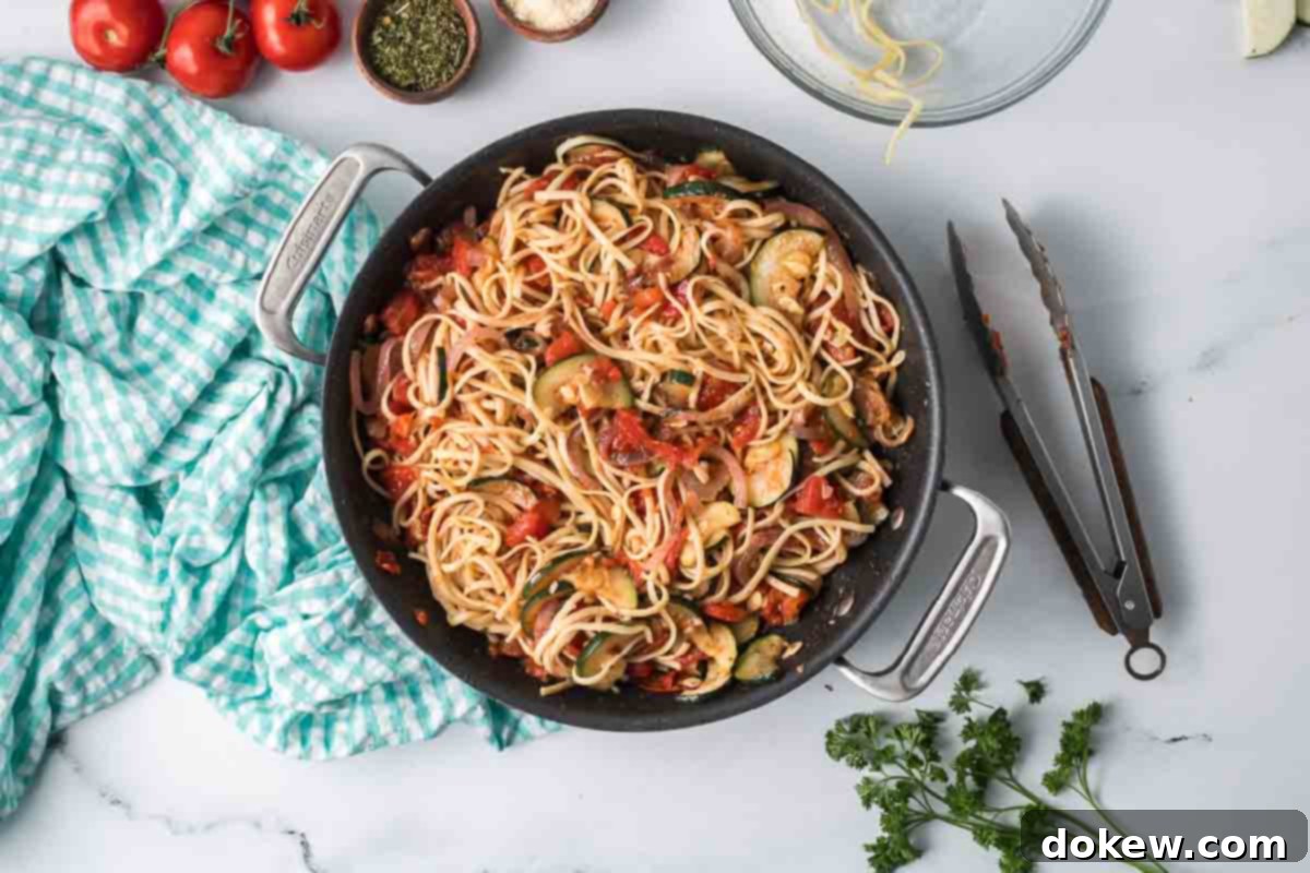 Fresh Zucchini Linguine 9 Cooked zucchini linguine, a delicious blend of pasta, tomatoes, zucchini, onion, and herbs, ready in a skillet.