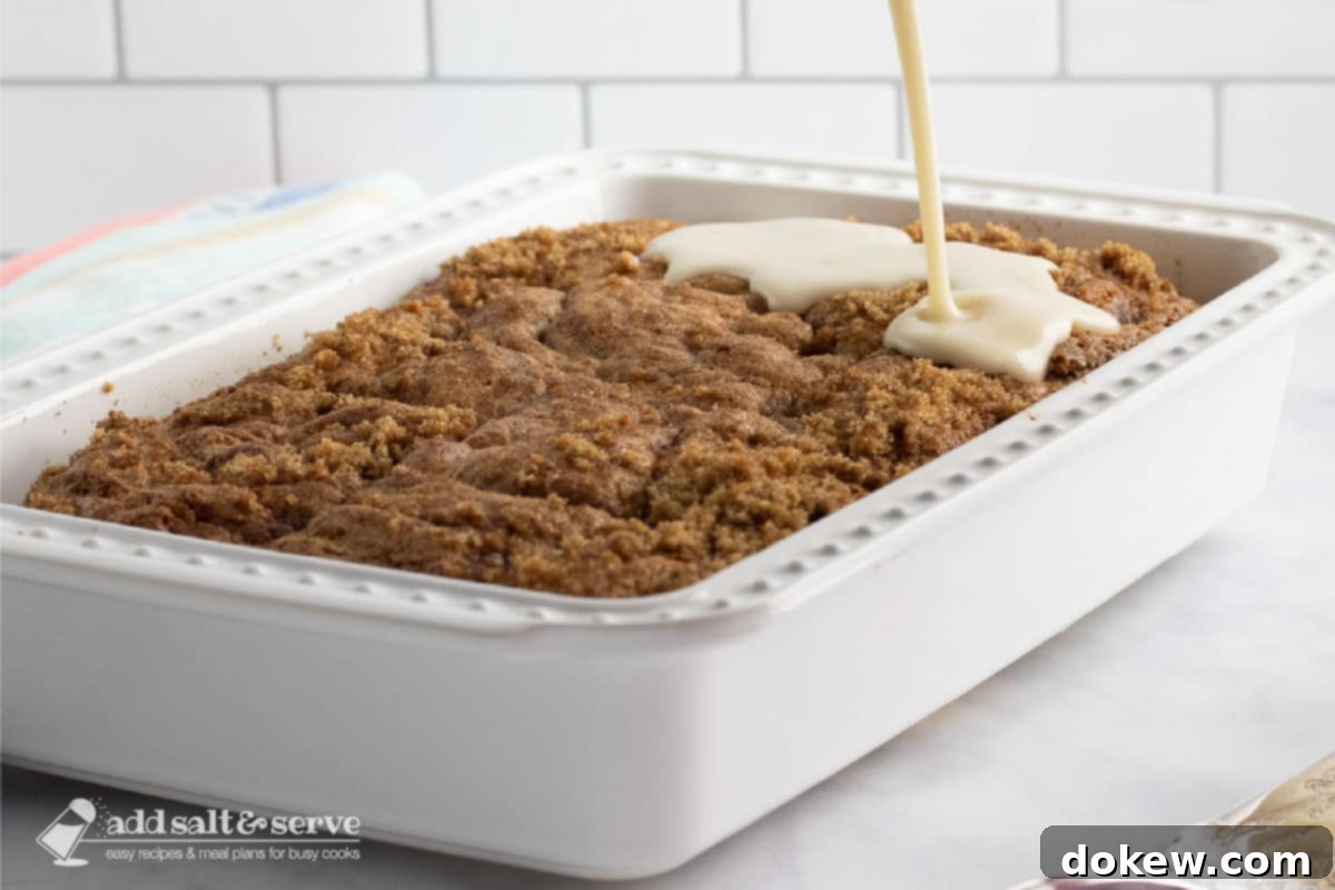 Cinnamon Honey Swirl Cake 6 A hot Honey Bun Cake, fresh out of the oven, with a glistening vanilla glaze being poured generously over its streusel-like cinnamon topping.