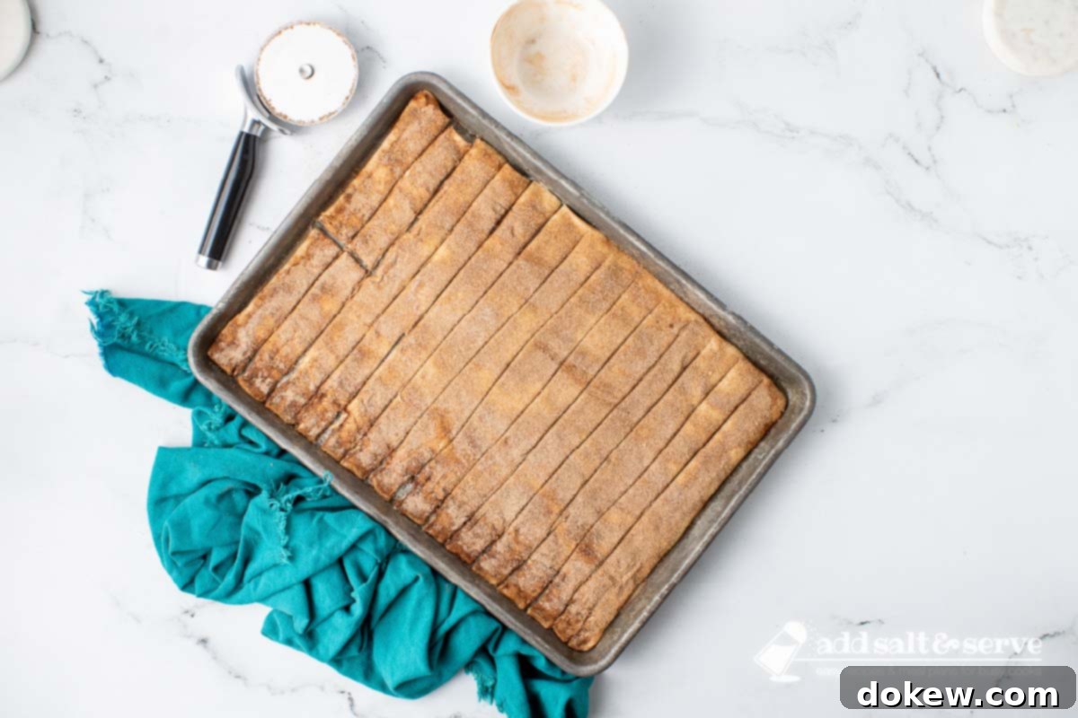 Quick Pizza Dough Cinnamon Twists 7 Cinnamon sticks cut into strips on a baking sheet, slightly separated and ready for baking.