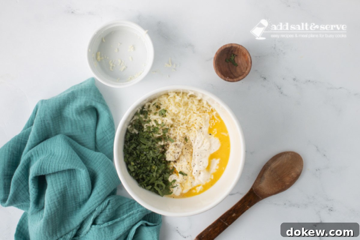 Golden Baked Alfredo Rotini 4 A medium-sized bowl with ricotta cheese, eggs, shredded mozzarella cheese, minced parsley, and salt and pepper before it has been mixed.