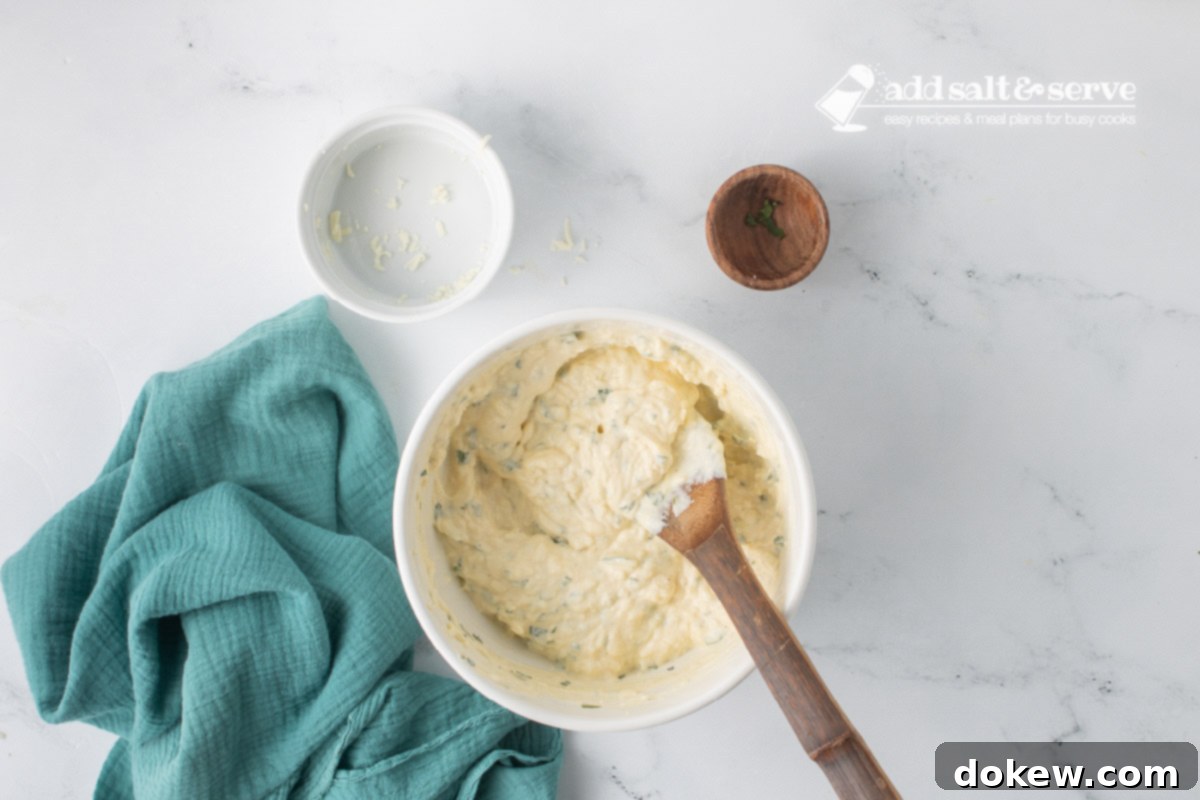 Golden Baked Alfredo Rotini 5 A medium-sized bowl with ricotta cheese, eggs, shredded mozzarella cheese, minced parsley, and salt and pepper after it has been mixed.