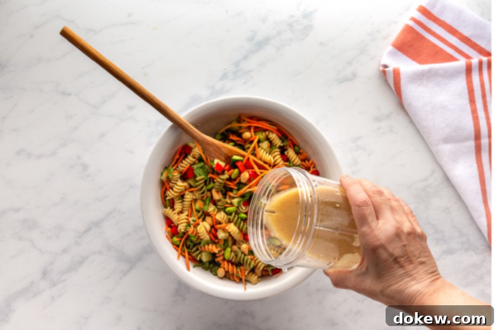 Thai Sesame Noodle Bowl 8 pouring sesame-ginger dressing over Thai pasta Salad