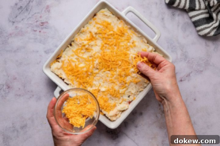 Effortless Make-Ahead Shepherd's Pie 9 sprinkling cheese on top of shepherd's pie before baking