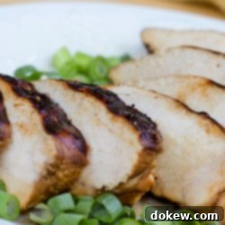 Freezer-Ready Flavor: Marinated Grilled Chicken 3 Sliced chicken breast on a white plate, garnished with chopped green onions.