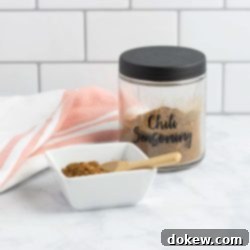 Legendary Terlingua Chili Starter 4 A jar of homemade chili seasoning beside a dish of the seasoning with a small wooden spoon.