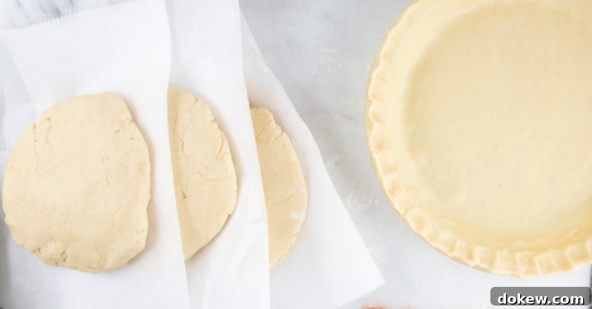Make-Ahead Buttery Flaky Pie Crust 5 Overhead image of unbaked pie crust in a pie pan to the right and thick circles of pie crust dough stacked with parchment paper in between ready for the freezer