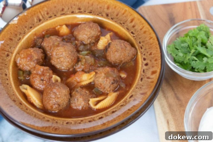 Bulk Meatballs Photo is a brown soup bowl with meatball soup, beside a cutting board. On the cutting board are two clear glass bowls with parsley and sour cream.