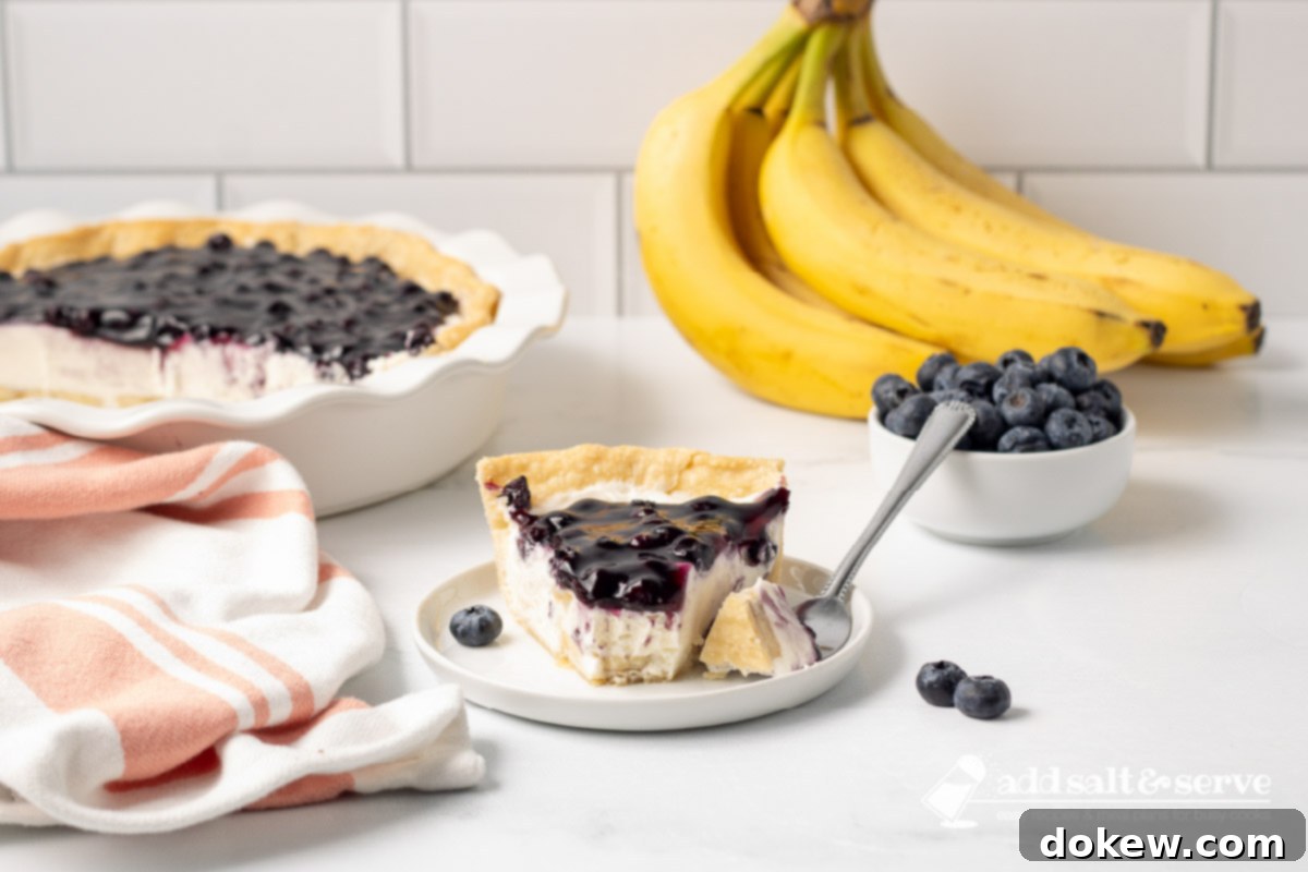 Blueberry Banana Cheesecake Pie 2 Slice of Blueberry Banana Pie with Cream Cheese with on a plate with a bite on a fork and the sliced pie in the background.