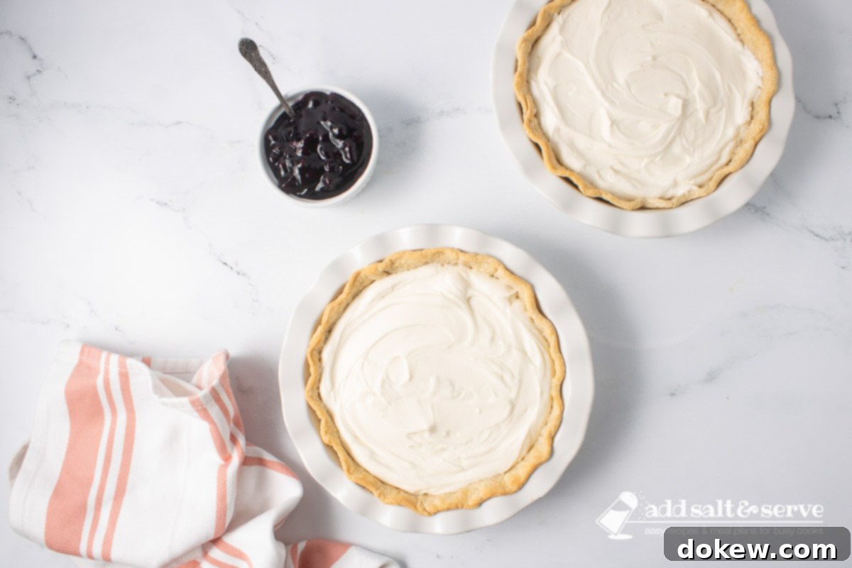 Blueberry Banana Cheesecake Pie 8 Two pie crusts full of cream cheese mixture with a bowl of blueberry pie filling to the side.