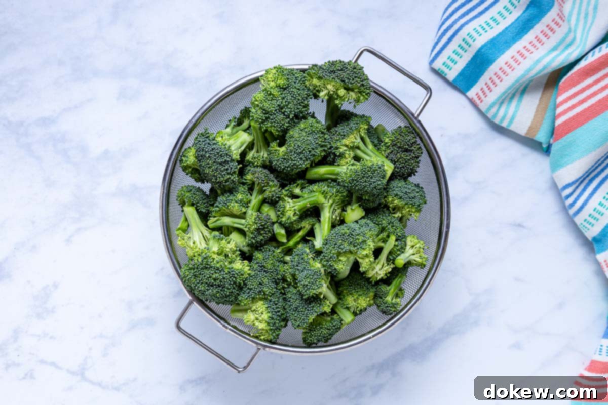 Crispy Garlic Roasted Broccoli 4 A strainer filled with freshly washed and chopped vibrant green broccoli florets, ready for roasting.