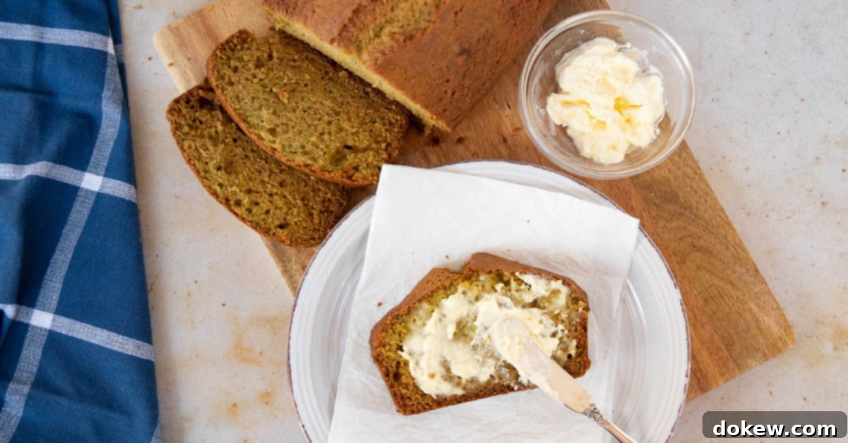 Overhead shot of a loaf of zucchini bread with a slice being spread with clotted cream