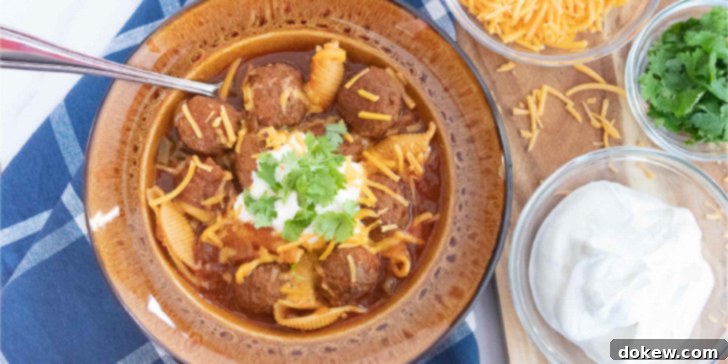 Crockpot Albondigas Soup (Mexican Meatball Soup) Overhead shot of albondigas soup (Mexican meatball soup) in a brown wide-rim bowl garnished with sour cream, grated cheddar cheese, and fresh cilantro