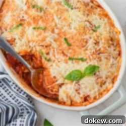 Skip The Boil Baked Frozen Ravioli 6 Casserole dish of baked frozen ravioli with a serving removed, revealing melted cheese and sauce.