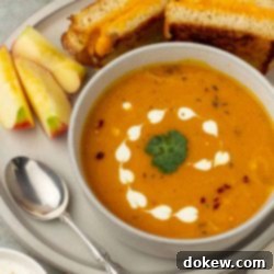 Sunshine Ginger Root Soup 7 Bowl of carrot sweet potato soup on a plate with apple slices and a grilled cheese sandwich.