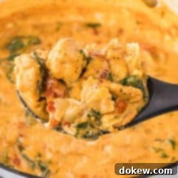 Tuscan Sunset Chicken 7 Creamy Tuscan chicken with sun-dried tomatoes, spinach, and mini farfalle in cream sauce in a pot with a serving on a spoon held over the pot and text Creamy Tuscan Chicken with Sun-dried Tomatoes.