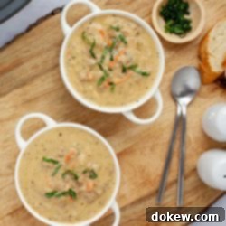 Creamy Crockpot Cheeseburger Soup 9 Two bowls of cheeseburger soup in white crocks beside fresh basil strips in a small bowl and two spoons.