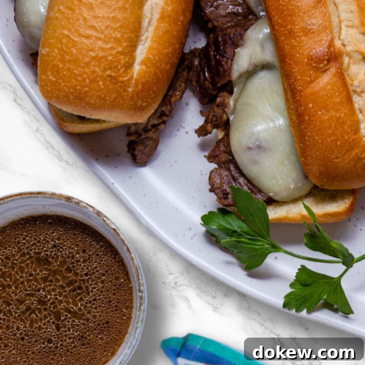 Easy Crockpot French Dip Tender Beef and Flavorful Au Jus 6 A completed slow cooker French Dip sandwich, generously filled with tender beef and melted provolone cheese, served alongside a small bowl of rich au jus for dipping.