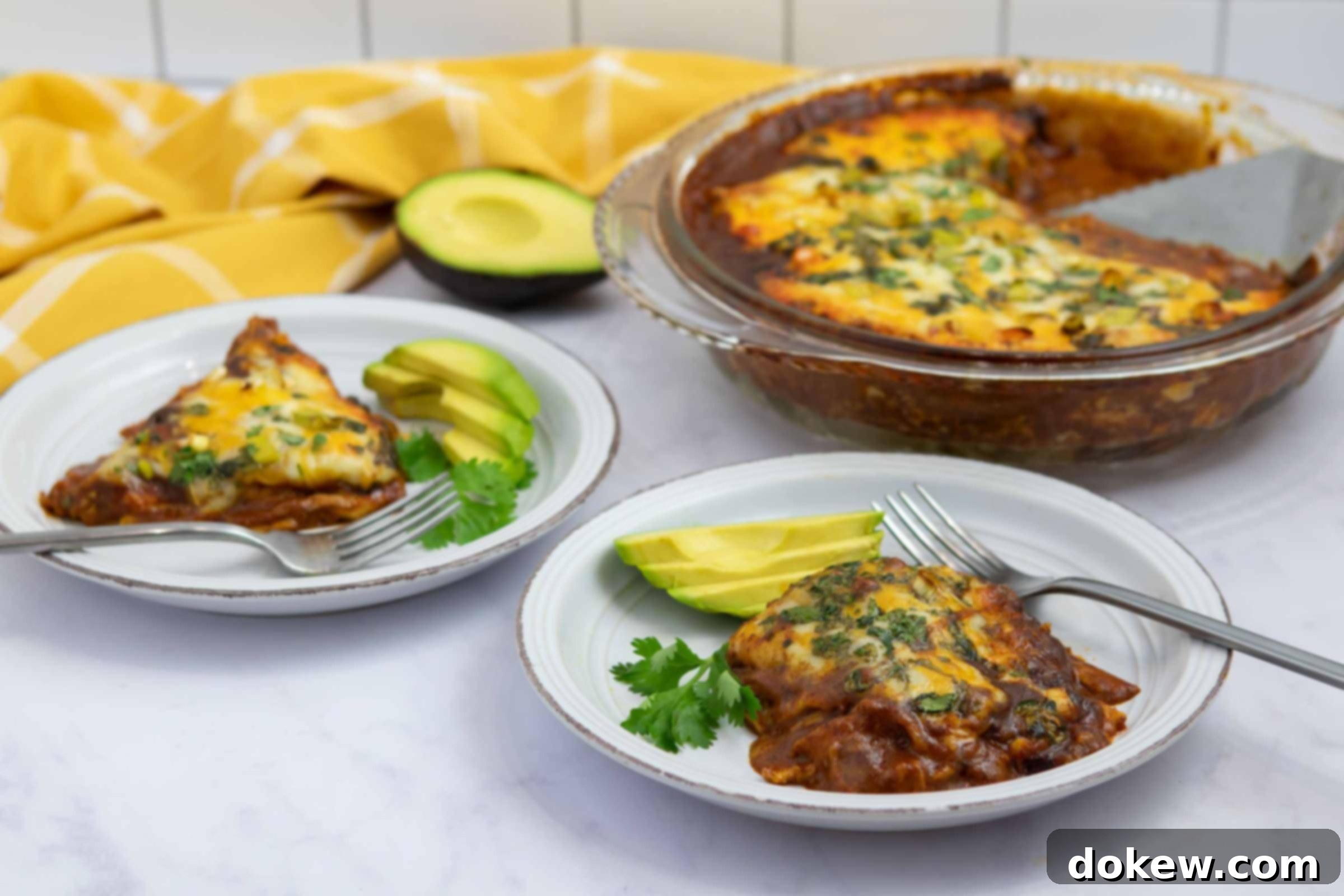Simple Stacked Chicken Enchilada Casserole 2 Two plates with chicken enchilada bake garnished with sliced avocado, demonstrating a delicious and easy meal.