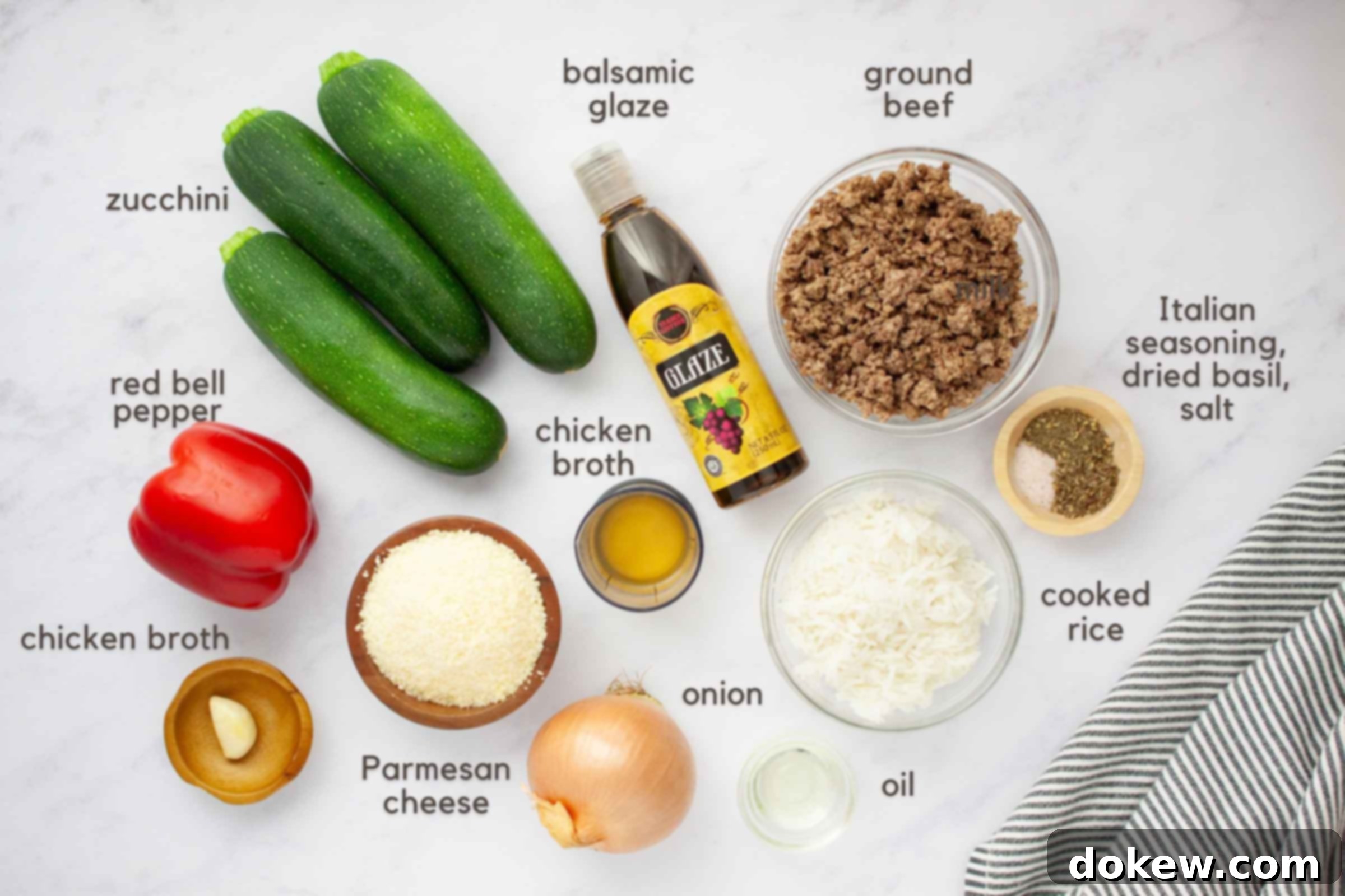 Zucchini Boats Bursting with Beef and Rice 3 Ingredients on a counter: 3 zucchini, 1 red bell pepper, 1 onion, 1 clove garlic, bowl of Parmesan cheese, chicken broth, oil, cooked rice, cooked ground beef, Italian seasoning, dried basil, and salt.