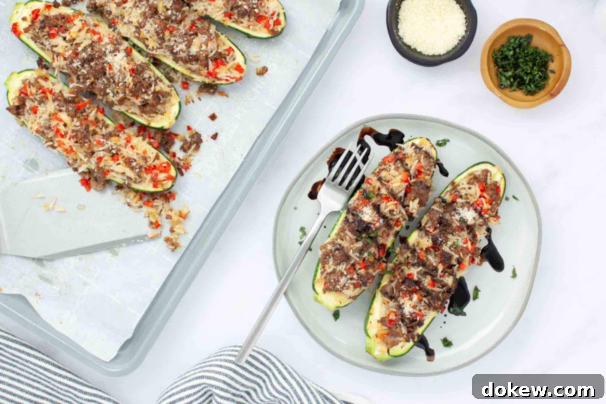 Zucchini Boats Bursting with Beef and Rice 6 Baked zucchini stuffed with a rice, ground beef, and vegetable mixture drizzled with balsamic glaze on a plate next to a baking sheet lined with parchment paper with more zucchini.