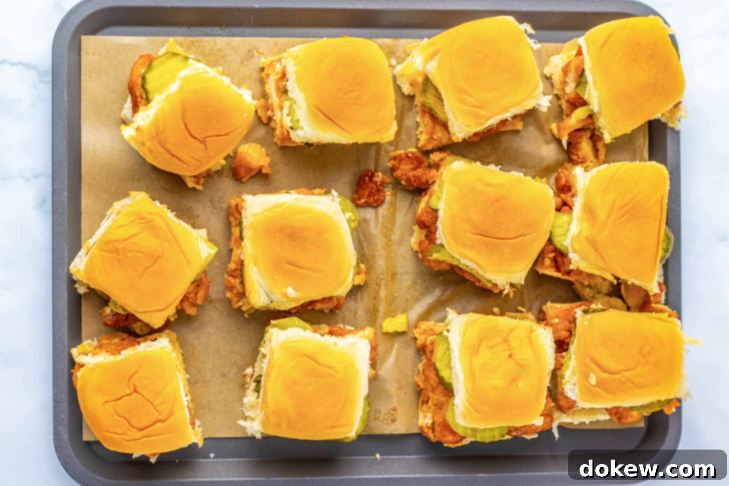 Sweet Heat Sliders: Done in a Flash 8 Overhead view of a dozen hot honey chicken sliders on a baking sheet.