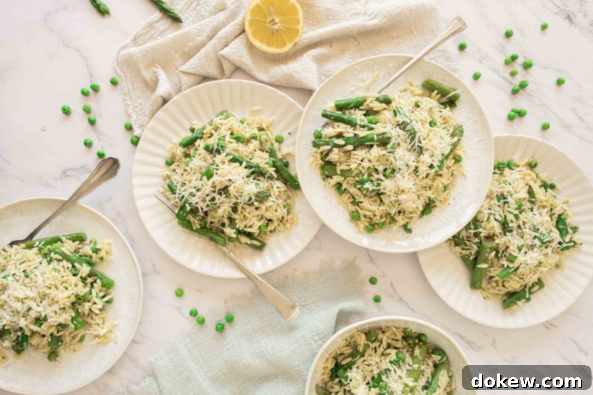 Spring Lemon Orzo with Asparagus, Peas, and Parmesan 6 Two plates of lemon orzo with peas and asparagus on a kitchen counter, beside a fresh half lemon, ready to be served.