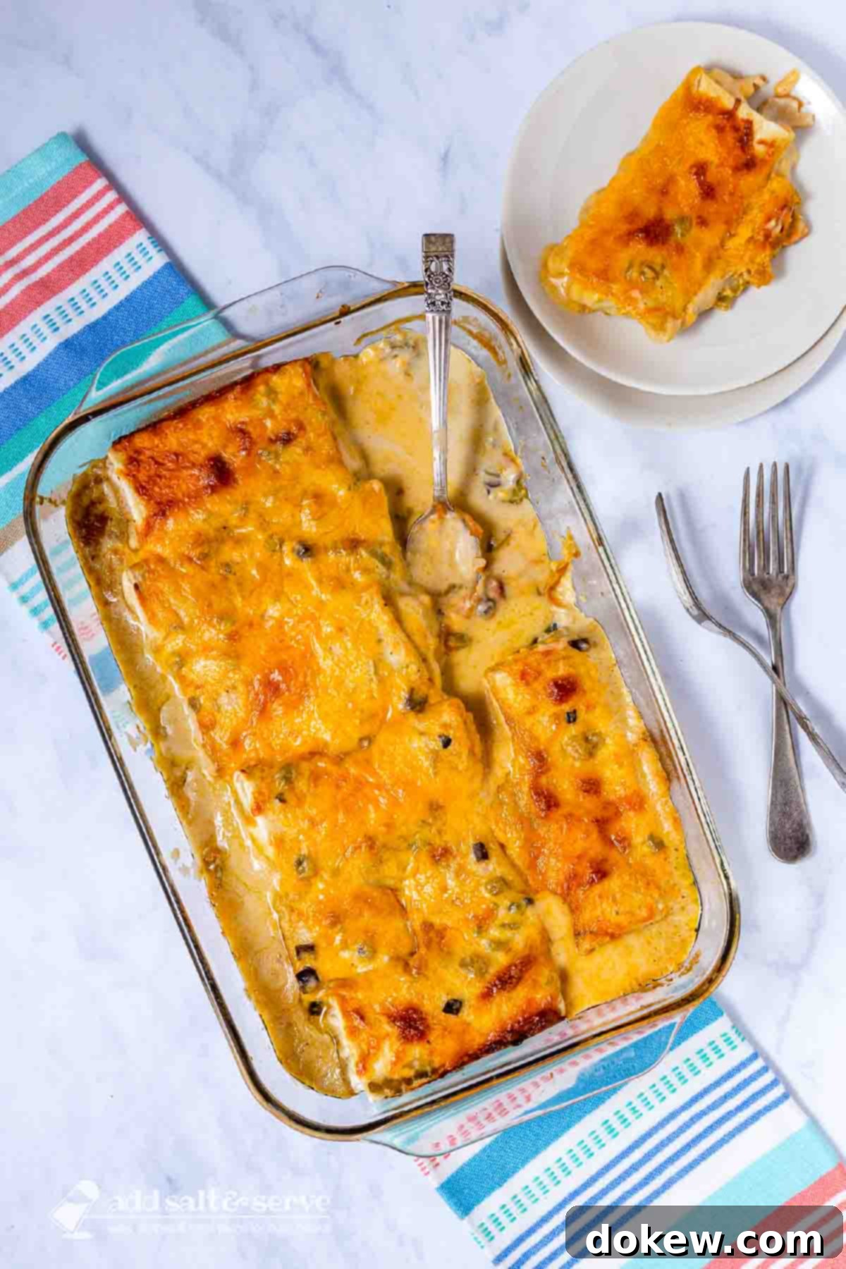 5 Malzemeli Pratik Burrito Güveci 5 Frozen burrito casserole in a baking dish with a serving on a plate beside it.